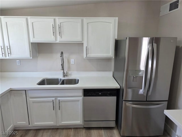 kitchen featuring stainless steel appliances, a sink, visible vents, white cabinets, and light countertops