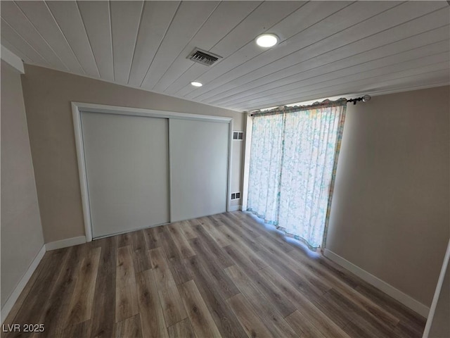 unfurnished bedroom with baseboards, a closet, visible vents, and wood finished floors