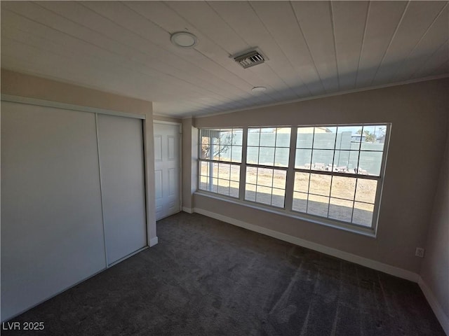 unfurnished bedroom featuring dark colored carpet, multiple windows, visible vents, and crown molding