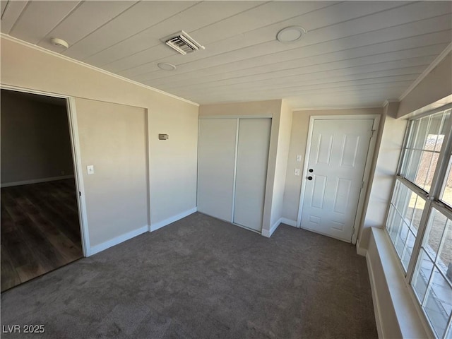 unfurnished bedroom with ornamental molding, carpet, a closet, and visible vents