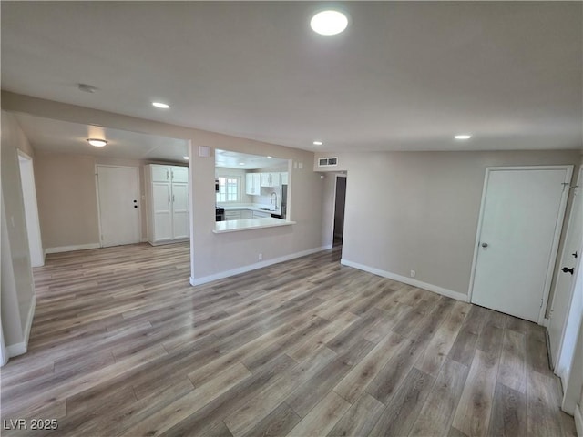 unfurnished living room featuring light wood-style flooring, baseboards, and recessed lighting