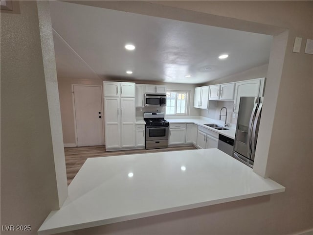 kitchen featuring a sink, white cabinets, light countertops, appliances with stainless steel finishes, and light wood finished floors