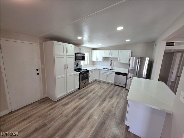 kitchen featuring appliances with stainless steel finishes, light wood-type flooring, a sink, and white cabinets