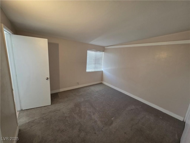 carpeted spare room with vaulted ceiling and baseboards