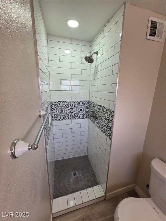 full bathroom with a stall shower, visible vents, toilet, and wood finished floors