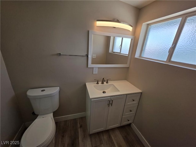 bathroom with toilet, baseboards, wood finished floors, and vanity