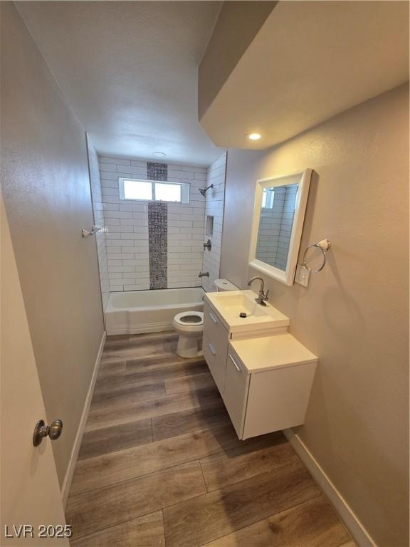 full bath with baseboards, toilet, wood finished floors, vanity, and shower / bathing tub combination