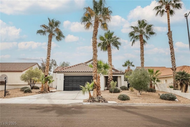 mediterranean / spanish home with a garage, driveway, a tiled roof, and stucco siding