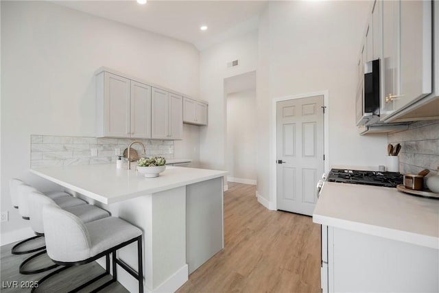 kitchen with a peninsula, light wood-style flooring, a breakfast bar, and light countertops