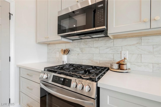 kitchen featuring stainless steel appliances, tasteful backsplash, light countertops, and white cabinetry