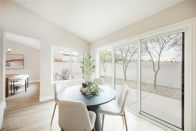 dining room featuring baseboards, vaulted ceiling, and light wood finished floors