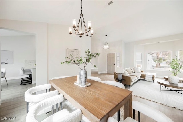 dining space featuring light wood finished floors, baseboards, and a chandelier