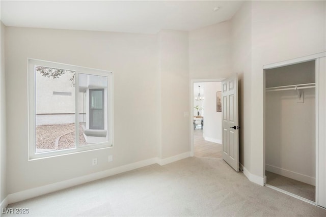 unfurnished bedroom featuring carpet floors, a high ceiling, a closet, and baseboards