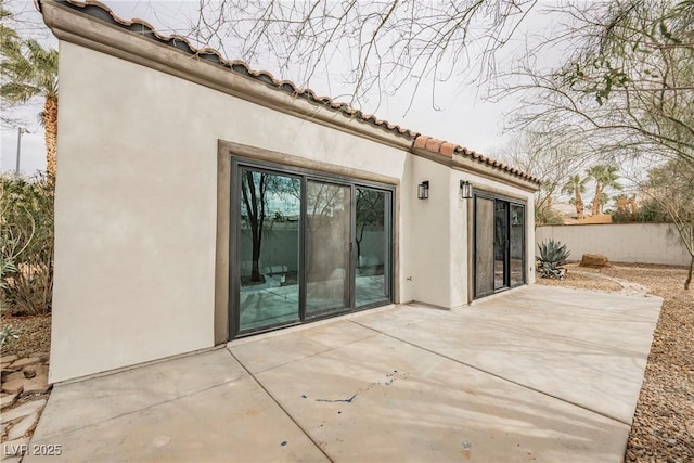 back of property featuring a patio, fence, a tile roof, and stucco siding