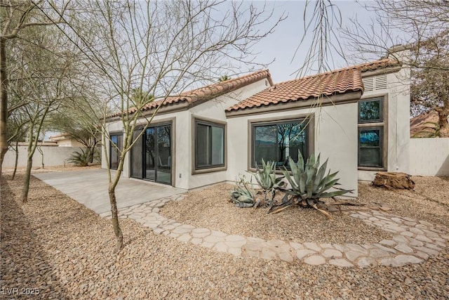 back of house featuring a patio, a tile roof, fence, and stucco siding