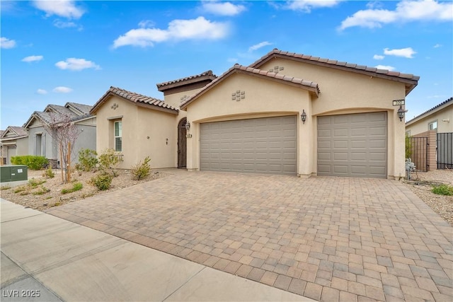 mediterranean / spanish-style house with an attached garage, central AC unit, decorative driveway, and stucco siding