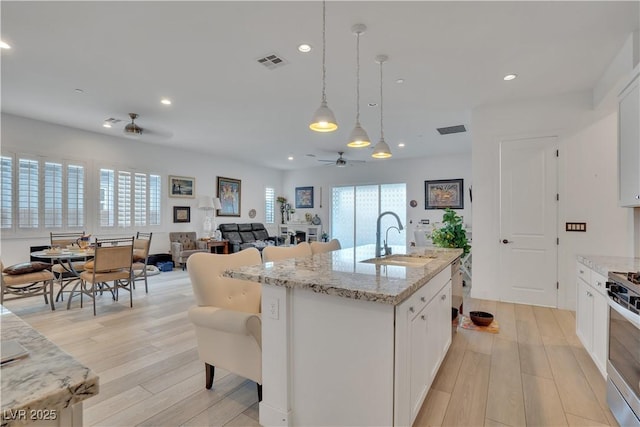 kitchen with ceiling fan, light wood-style flooring, a sink, visible vents, and stainless steel range with gas stovetop