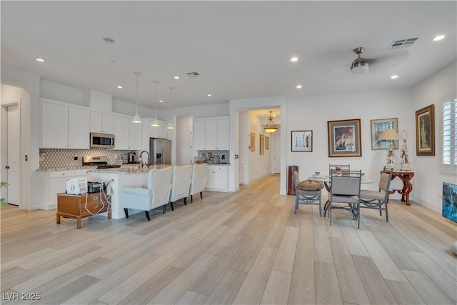 kitchen with visible vents, appliances with stainless steel finishes, backsplash, and a breakfast bar area