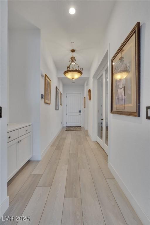 hall with light wood-type flooring and baseboards