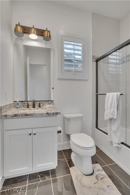 full bath with baseboards, shower / bath combination with glass door, vanity, and toilet