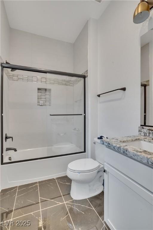 full bathroom featuring marble finish floor, bath / shower combo with glass door, vanity, and toilet