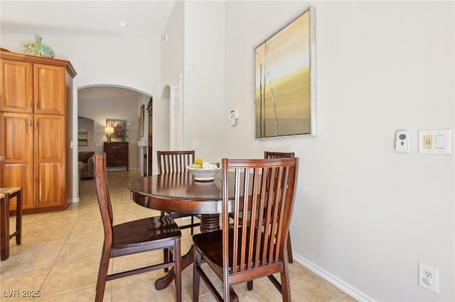 dining room with arched walkways, baseboards, and light tile patterned floors