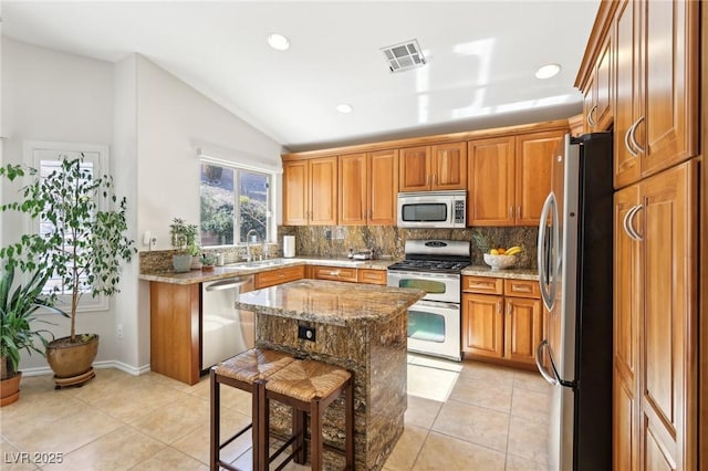 kitchen featuring light stone counters, appliances with stainless steel finishes, visible vents, and tasteful backsplash