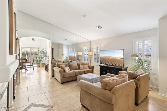 living area featuring baseboards, visible vents, a ceiling fan, and light tile patterned flooring