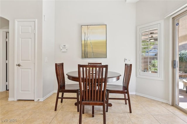 dining room with baseboards, arched walkways, and light tile patterned flooring