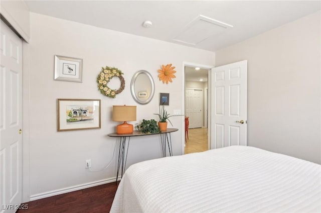 bedroom featuring a closet, wood finished floors, attic access, and baseboards