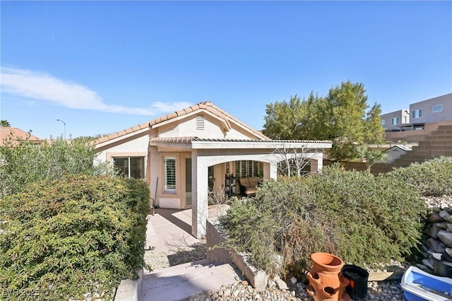 view of front of property featuring a patio area, a tile roof, and stucco siding