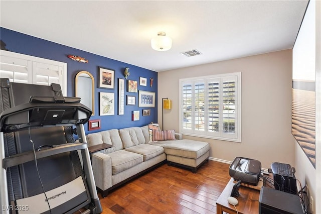 living area featuring hardwood / wood-style floors, visible vents, and baseboards