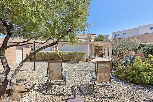 rear view of property featuring a patio, fence, a tile roof, and stucco siding