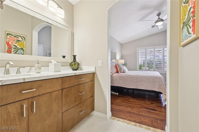 ensuite bathroom featuring lofted ceiling, ensuite bath, ceiling fan, tile patterned flooring, and vanity