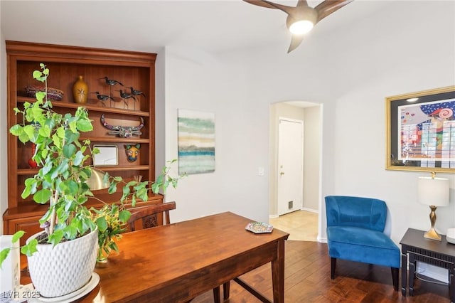 office with arched walkways, wood finished floors, and a ceiling fan