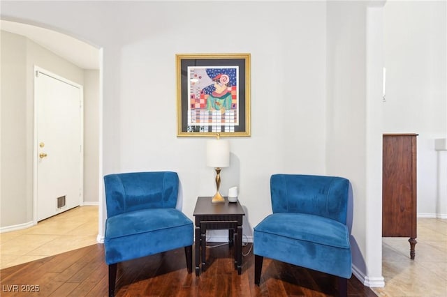 living area featuring arched walkways, wood finished floors, visible vents, and baseboards