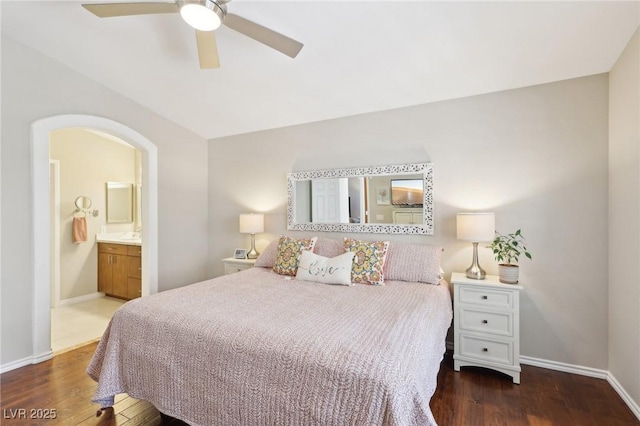 bedroom with connected bathroom, baseboards, and wood finished floors