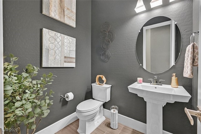 bathroom featuring wood finished floors, toilet, and baseboards