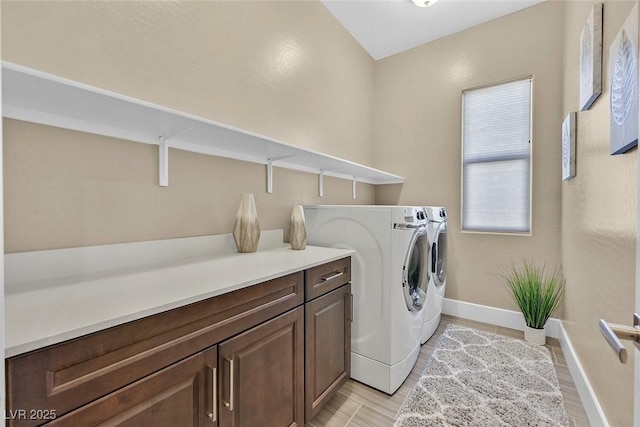 clothes washing area featuring washer and clothes dryer, light wood-type flooring, cabinet space, and baseboards