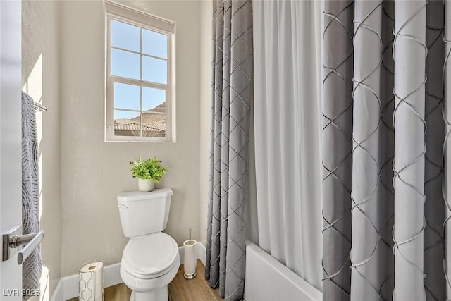 full bathroom featuring shower / bath combo, wood finished floors, toilet, and baseboards