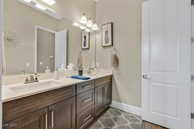 bathroom featuring double vanity, baseboards, and a sink