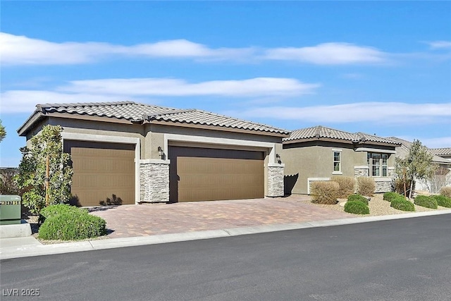 view of front of home with stone siding, a tiled roof, decorative driveway, and stucco siding