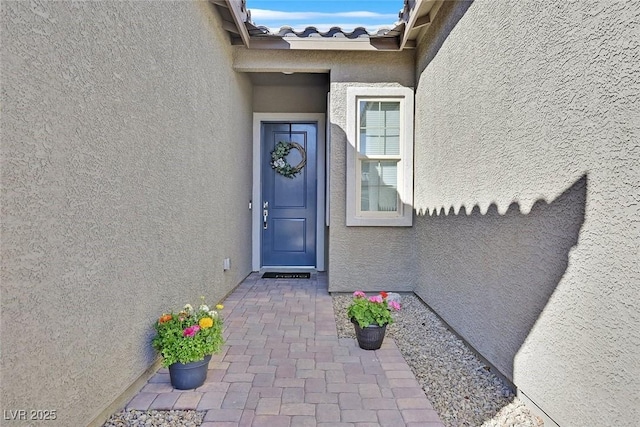 property entrance with a tiled roof and stucco siding