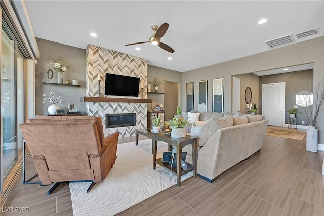 living area featuring a large fireplace, ceiling fan, baseboards, and recessed lighting