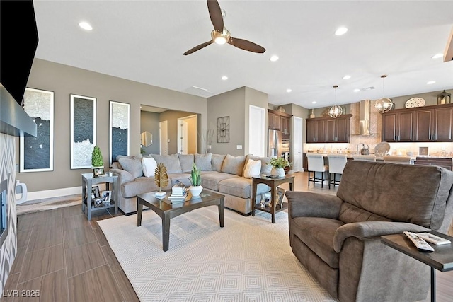 living room featuring baseboards, a ceiling fan, and recessed lighting