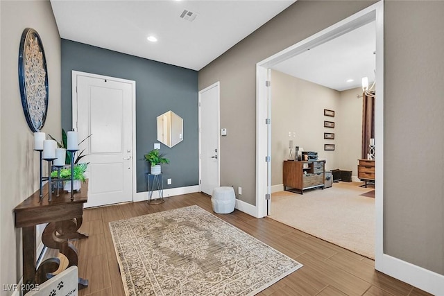 foyer featuring visible vents, baseboards, and wood finished floors