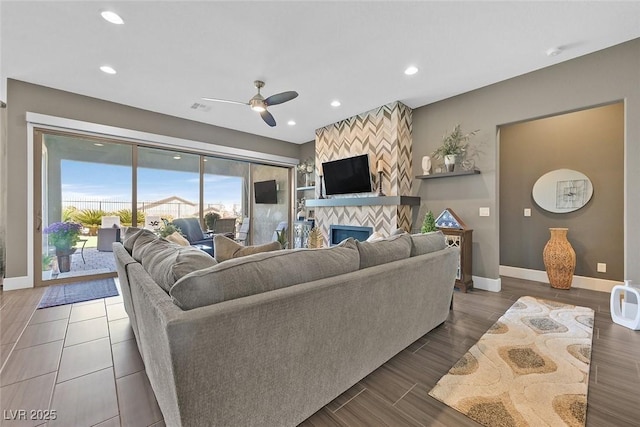 living room featuring recessed lighting, a ceiling fan, a large fireplace, wood finished floors, and baseboards