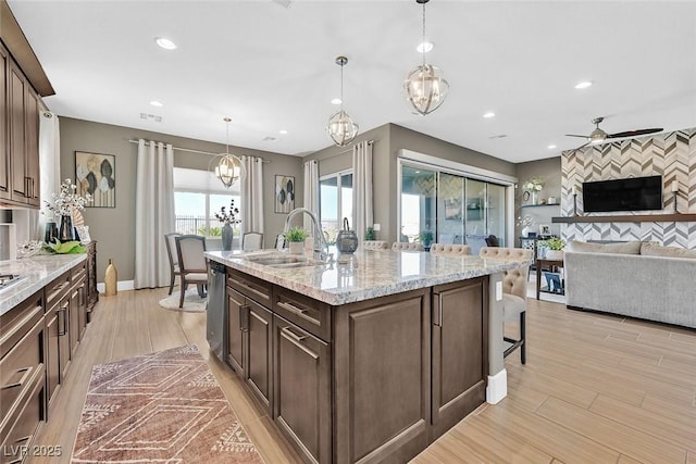 kitchen featuring an accent wall, a kitchen breakfast bar, a sink, stainless steel dishwasher, and recessed lighting