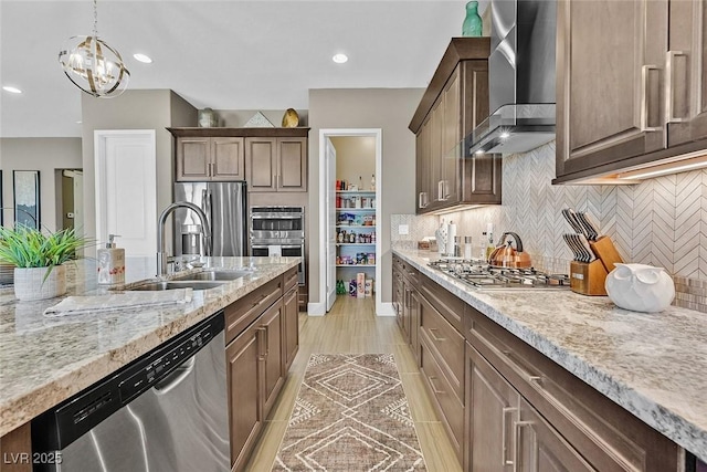 kitchen featuring stainless steel appliances, wall chimney range hood, backsplash, and light stone counters