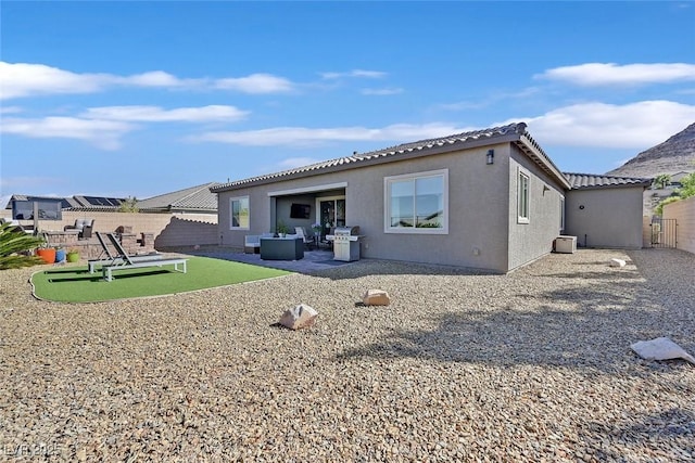 rear view of property with stucco siding, a tiled roof, fence, and a patio